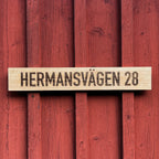 Innbränd fasadskylt på planhyvlad ek.